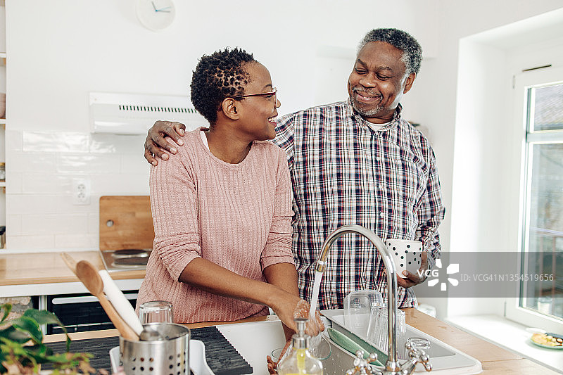 非裔美国老年妇女洗碗和放松与她的丈夫图片素材