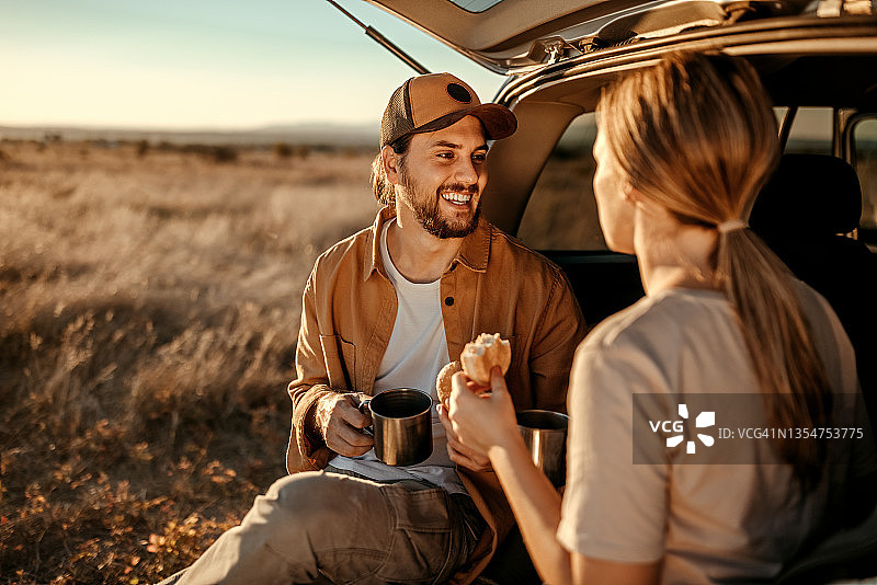 幸福的夫妇在野外的汽车后备箱吃早餐图片素材