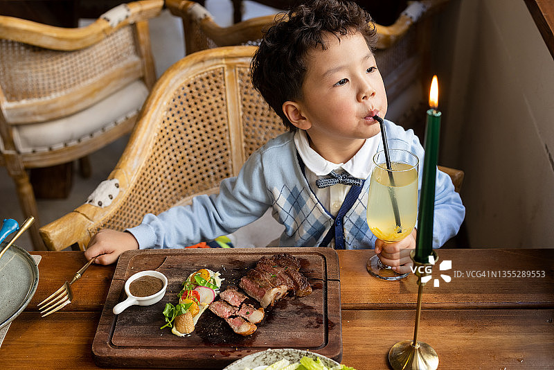 一个小男孩在餐厅吃牛排图片素材