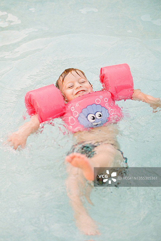 小红发幼儿漂浮在他的背部与浮在水牛城，纽约游泳池图片素材