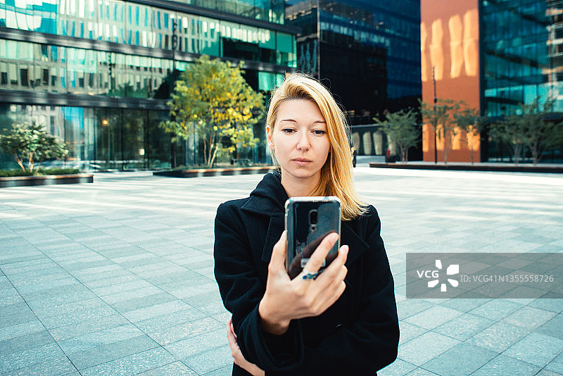自信的年轻女商人在市中心使用手机图片素材