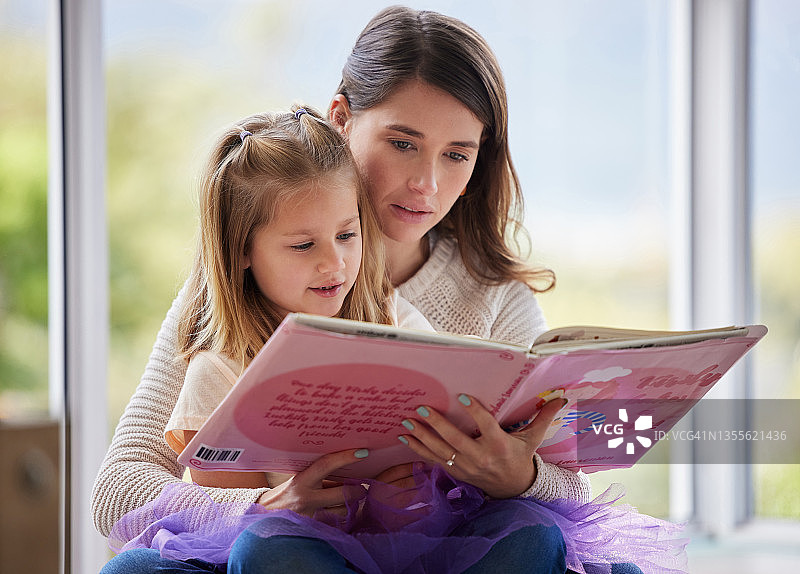 一个年轻的母亲和她的女儿在家里读书图片素材