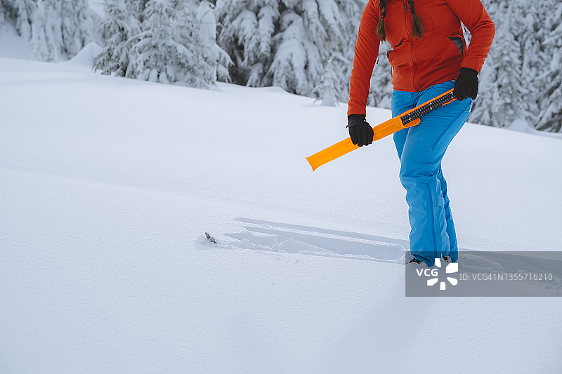 一个偏远地区的滑雪者从防护盒中取出雪崩探测器图片素材