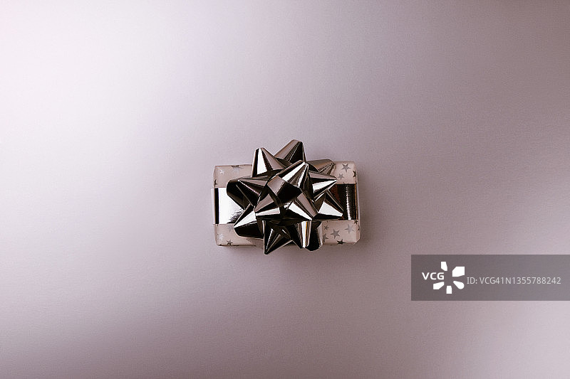 白色礼盒与星星和银色系蝴蝶结在灰色金属的背景。图片素材