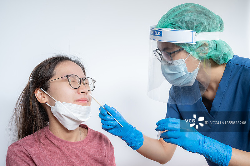 医护人员试图从亚洲妇女身上提取鼻拭子以检测covid-19感染诊断。图片素材