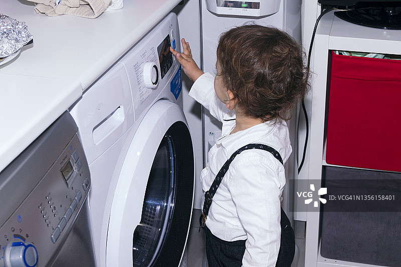 小孩操作洗衣机用具。图片素材
