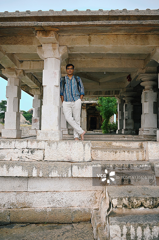 卡纳塔克邦汉比，一名男子站在古印度教寺庙的一根柱子旁图片素材