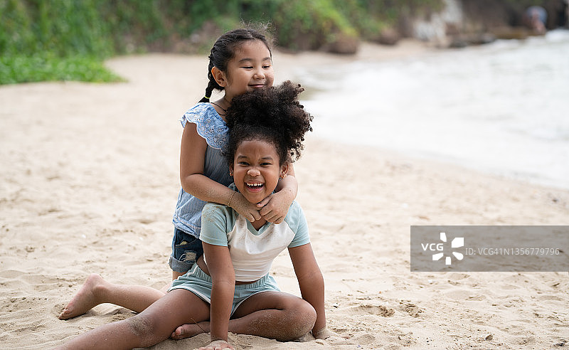 两个年轻女孩在海滩上玩得很开心。图片素材