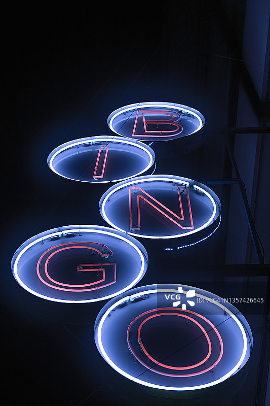 霓虹灯复古蓝、白、红的宾果广告灯与字母周围的圆圈。夜灯摄影。光晕效果，盛开的光。图片素材