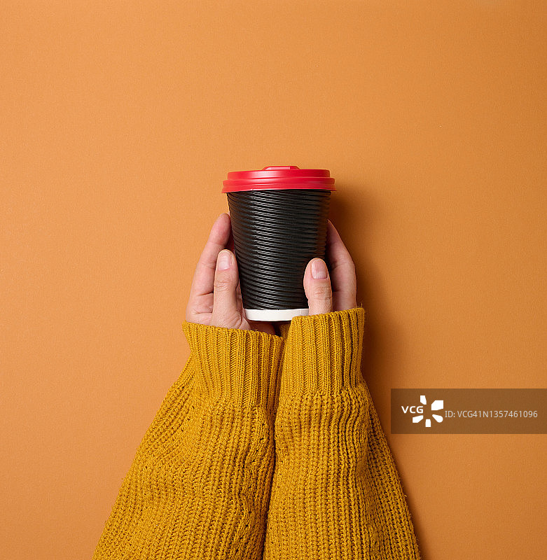 手拿着纸纸板的棕色杯子盛咖啡。环保餐具图片素材