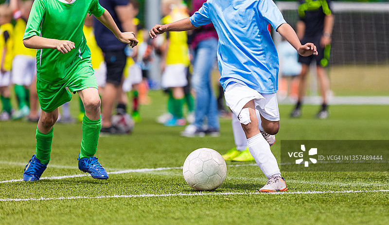 小男孩在踢足球。孩子们在运动中获得乐趣。快乐的孩子们在足球比赛中竞争。足球运动员。足球运动员在奔跑和踢球之间的比赛。足球学校图片素材