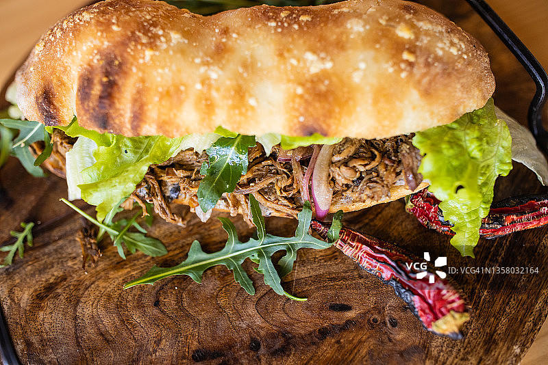 质朴的牛肉三明治，装在木盘子里，旁边放着辣椒图片素材