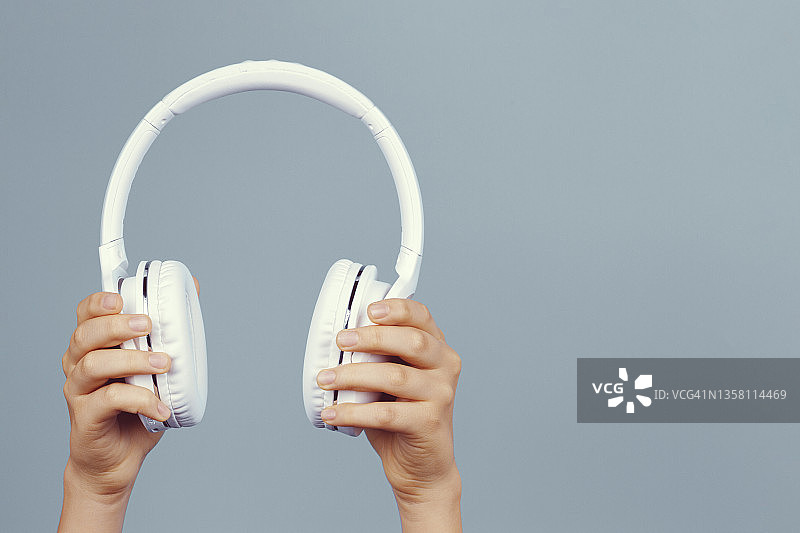 手握现代白色无线耳机在浅灰色的背景图片素材