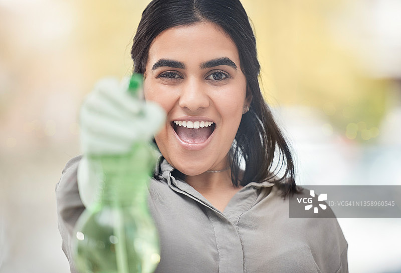 一个年轻女子在家里清洁时拿着一个喷雾瓶图片素材