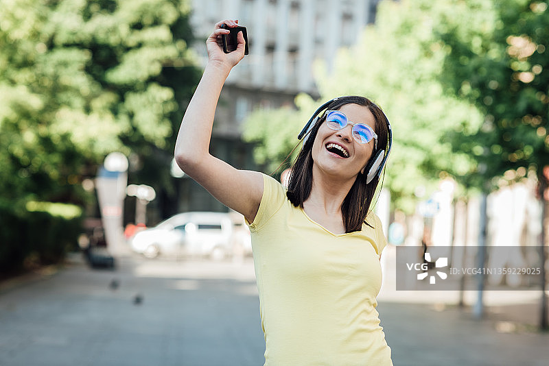 一个快乐的女孩在她的音乐移动应用程序上选择一首歌的肖像图片素材