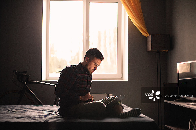 一名男子坐在家里的床上使用笔记本电脑图片素材