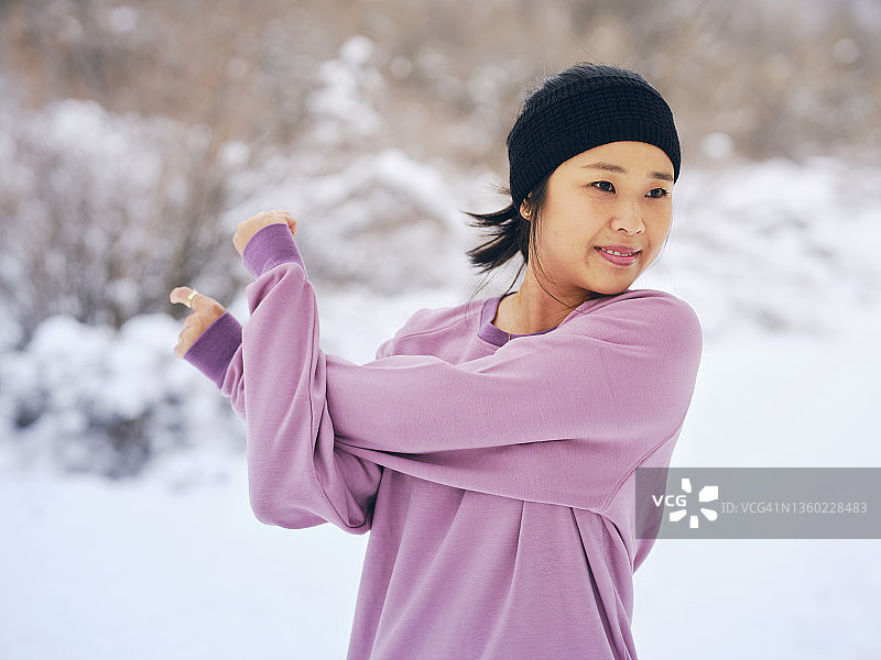 一个女人在冬季跑步前伸展身体图片素材