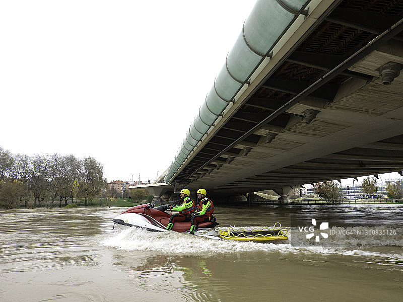 两名救援人员用摩托艇在桥下追踪河流图片素材