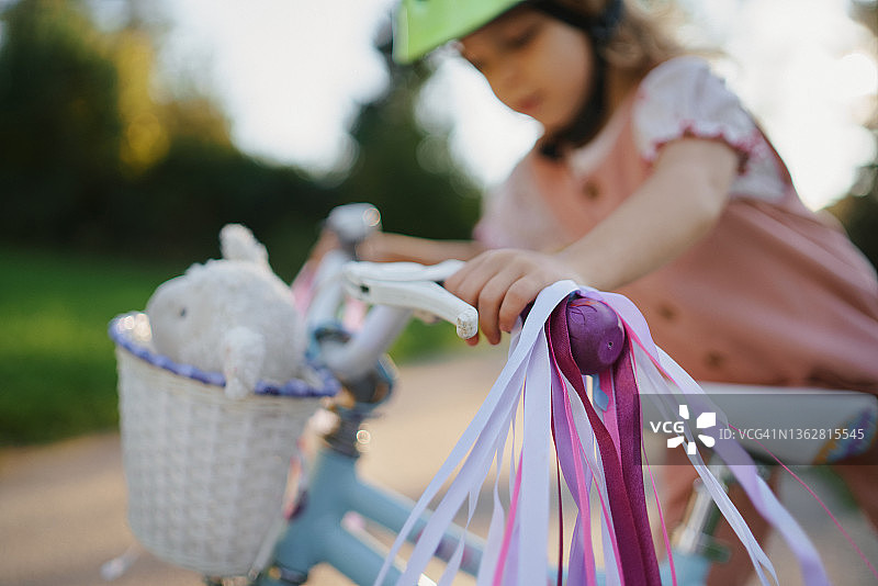 小女孩骑自行车，注意车把上的饰带。图片素材
