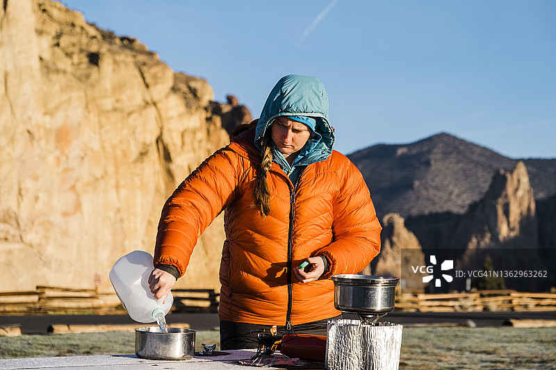 一名女露营者在做早餐时把水倒进锅里图片素材