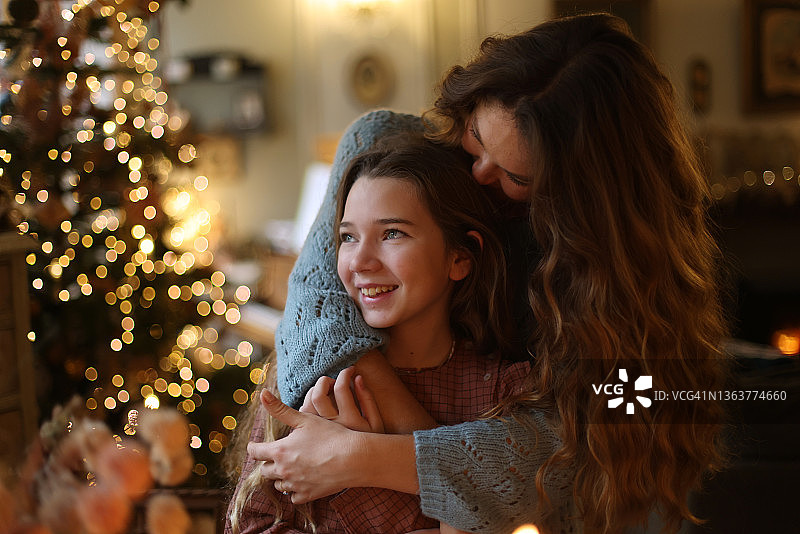 一位母亲在圣诞树前亲吻她的女儿图片素材