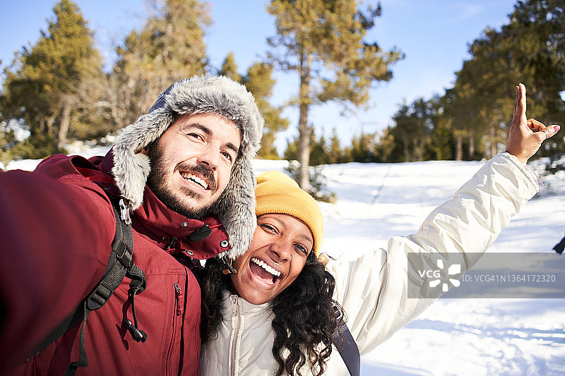 跨种族的年轻夫妇在雪景中自拍。图片素材