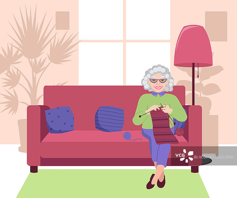 奶奶织微笑。一位老妇人正坐在沙发上，手里拿着编织针。手工制作的概念。图片素材