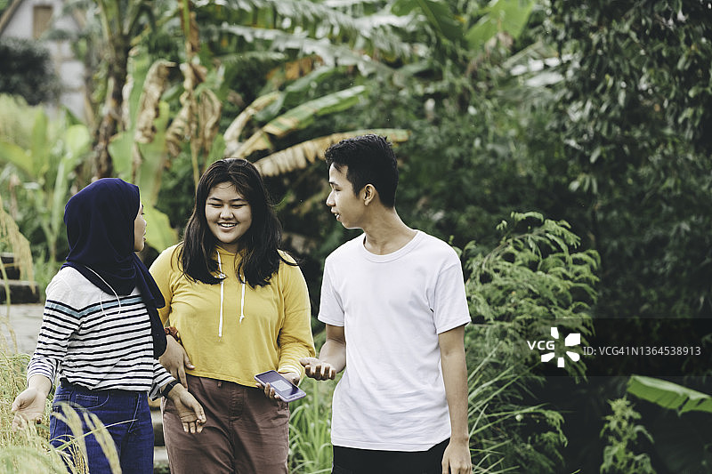 三个亚洲年轻人在村里聊天散步图片素材