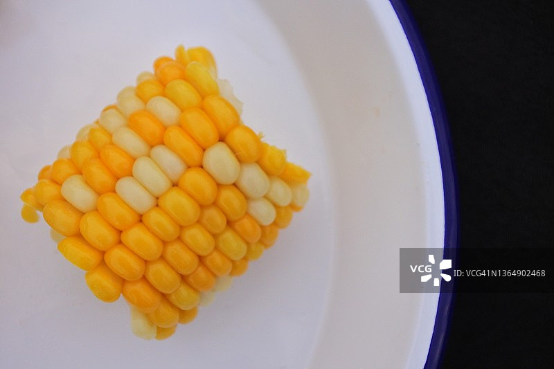 新鲜煮熟的玉米棒盛在白色盘子里图片素材