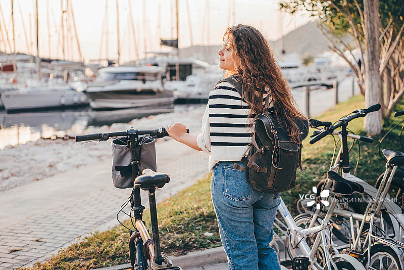 在海港骑自行车的年轻女子。图片素材