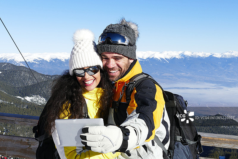 年轻的滑雪情侣在雪山顶上自拍图片素材