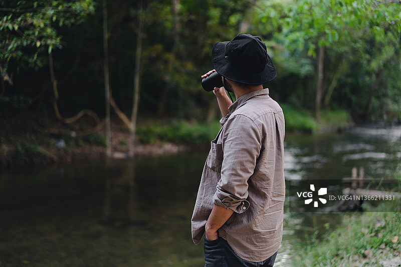 男子喜欢在森林里的河边喝咖啡，参加夏令营图片素材