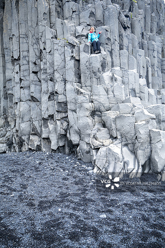 冰岛，成熟的女人坐在Reynisfjara黑沙滩上的Gardar玄武岩柱上。图片素材