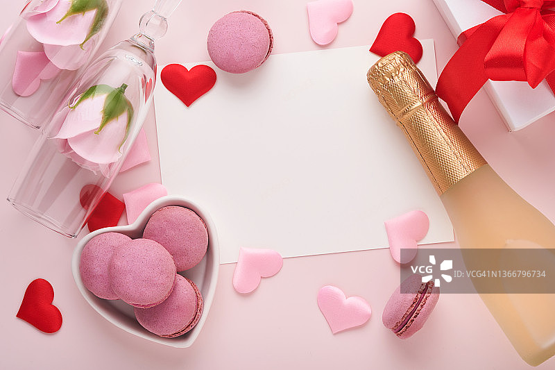 情人节贺卡香槟瓶，礼品盒，红丝带和信封空白的笔记模型内粉红色的背景。俯视图与空间的问候。贺卡与复制空间图片素材