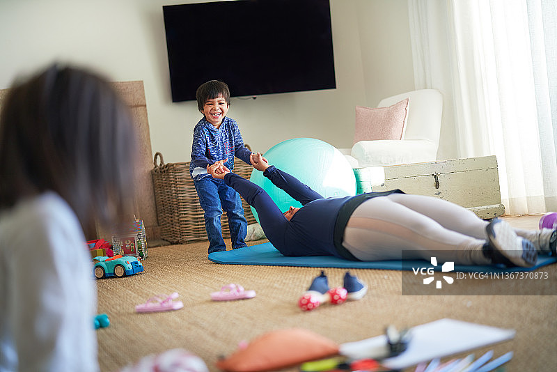 男孩和妈妈在客厅的瑜伽垫上玩耍图片素材