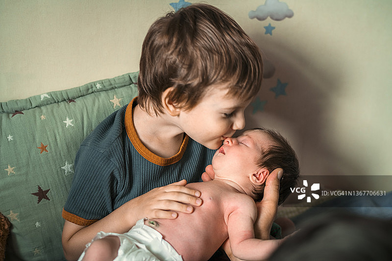 小男孩亲吻他刚出生的妹妹图片素材