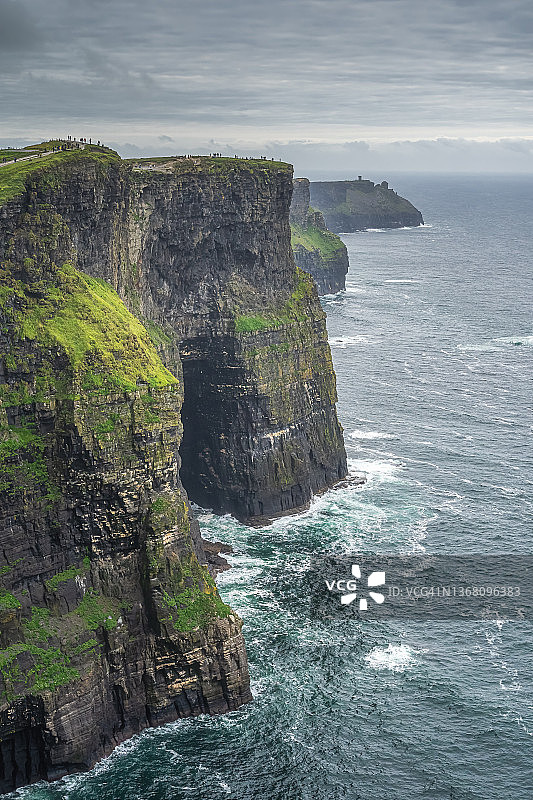 游客走在莫赫悬崖上，瞭望塔莫赫塔在远处，爱尔兰图片素材