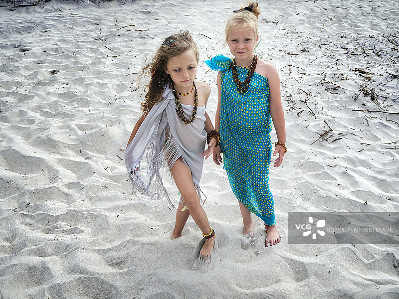 波兰波罗的海海岸，两个女孩站在沙滩上，穿着纱笼，戴着琥珀首饰图片素材