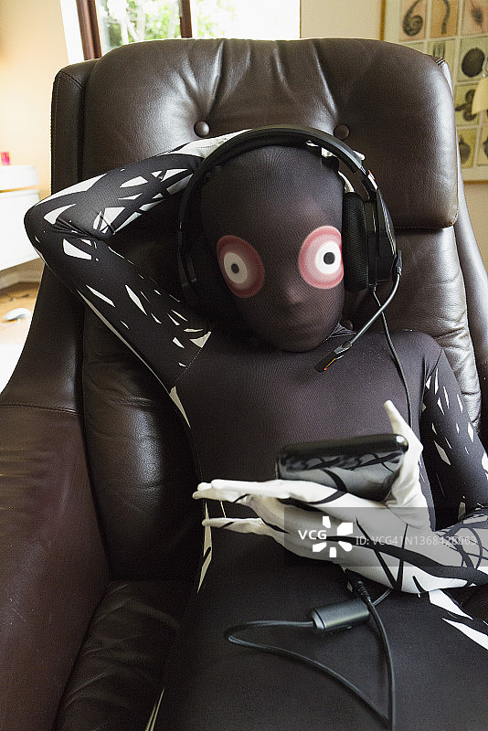 穿着外星人服装的男孩戴着耳机坐在皮椅上图片素材