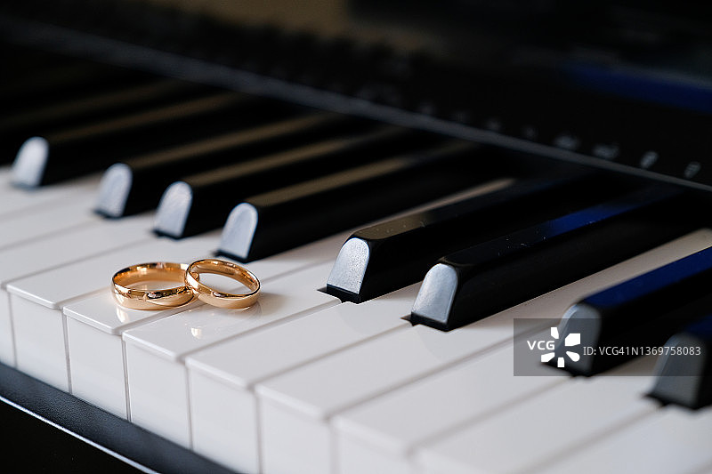金婚戒放在钢琴琴键上。浪漫，婚礼或订婚。爱的宣言。求婚。图片素材
