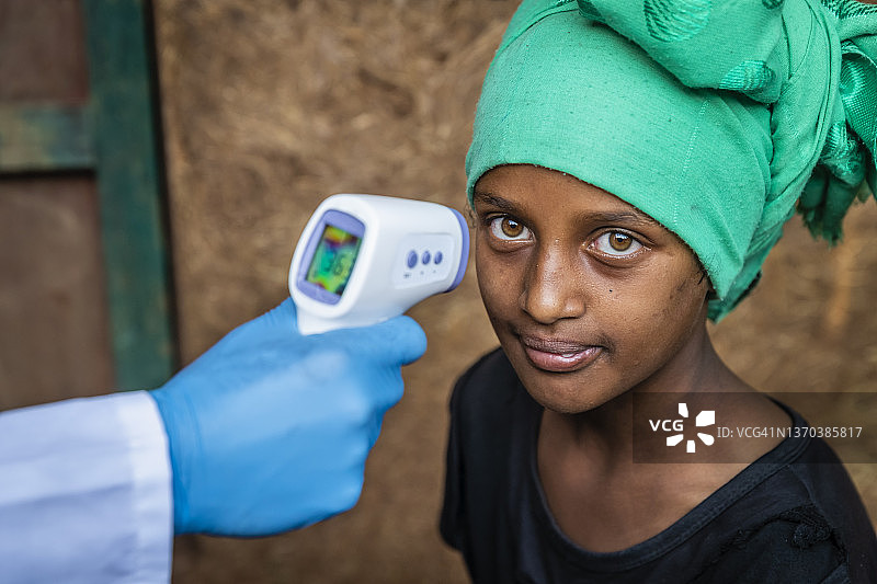 东非偏远村庄的男医生给女孩量体温图片素材