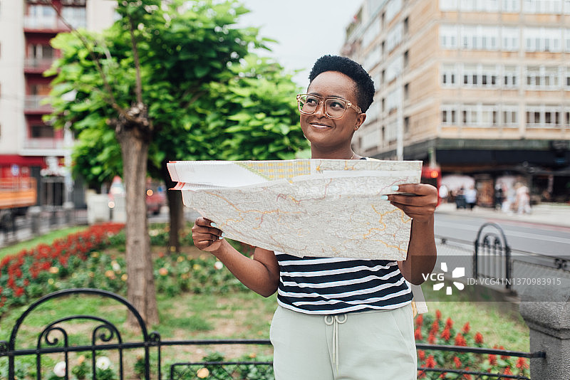 一个快乐的非洲裔美国女孩的肖像在旅游时看地图图片素材