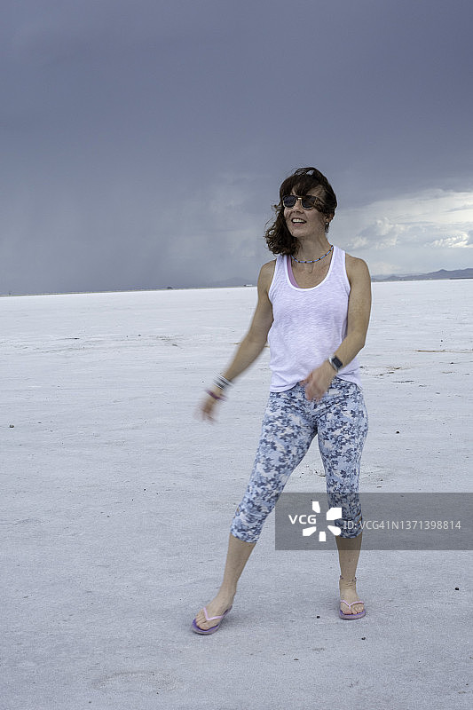 在犹他州的博纳维尔盐滩上，一名女子微笑着散步图片素材