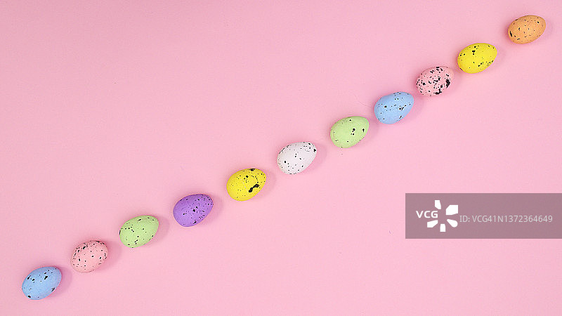 复活节彩蛋整齐地安排在柔和明亮的粉红色背景上。平铺春假概念。图片素材