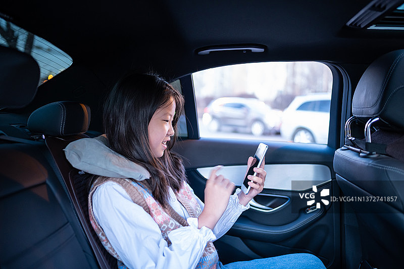 亚洲可爱的小女孩在车里用智能手机图片素材