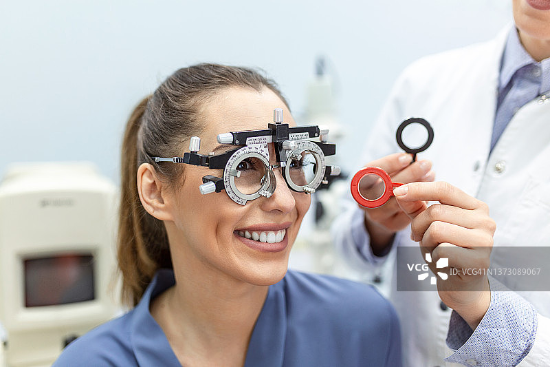 眼科医生用验光师试验架检查妇女。女患者在眼科门诊检查视力图片素材