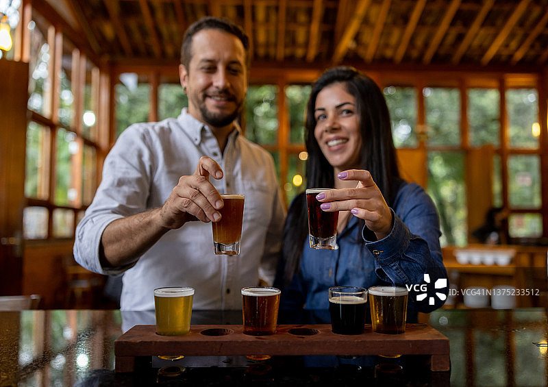 一对快乐的夫妇在啤酒厂参观时试着喝啤酒图片素材