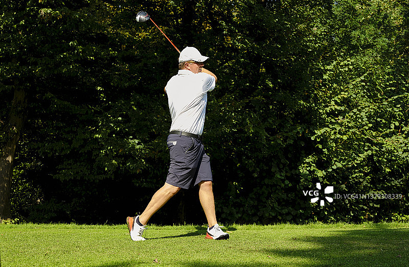 高尔夫球手在高尔夫球场上准备开球。高尔夫球手用高尔夫球杆击球以达到完美的击球效果。图片素材