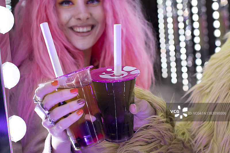 快乐时尚的女人与粉红色的头发持有泡沫茶在一次性杯子图片素材