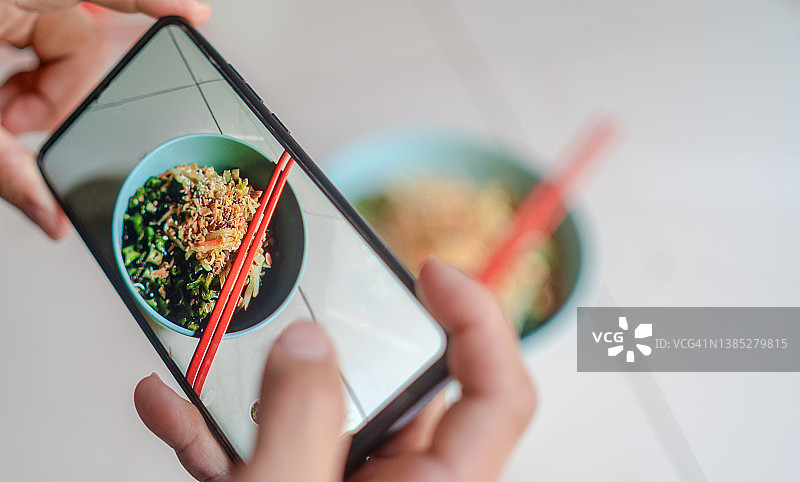 一名亚洲女性正在用智能手机拍摄晚餐图片素材